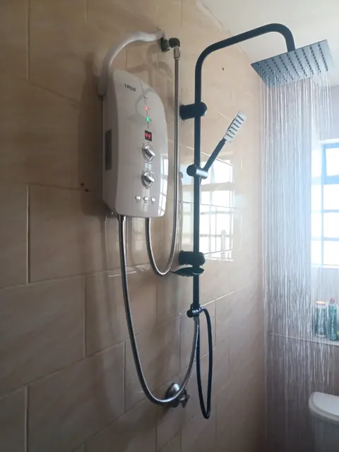 Black rain shower running with digital instant water heater at 44°C