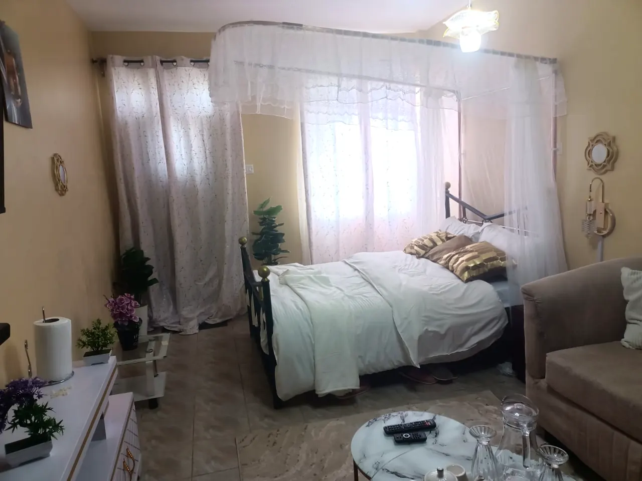 Canopy bed dressed in white linen with gold accent cushions